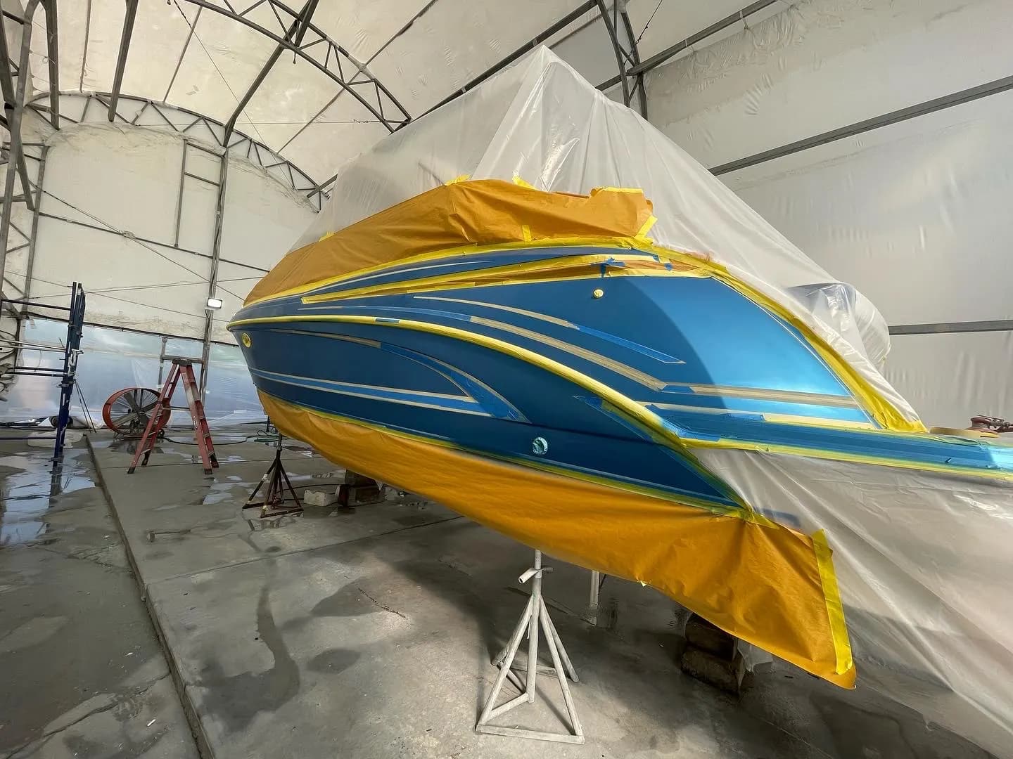 Hull graphics masked with protective tape during marine refinishing preparation
