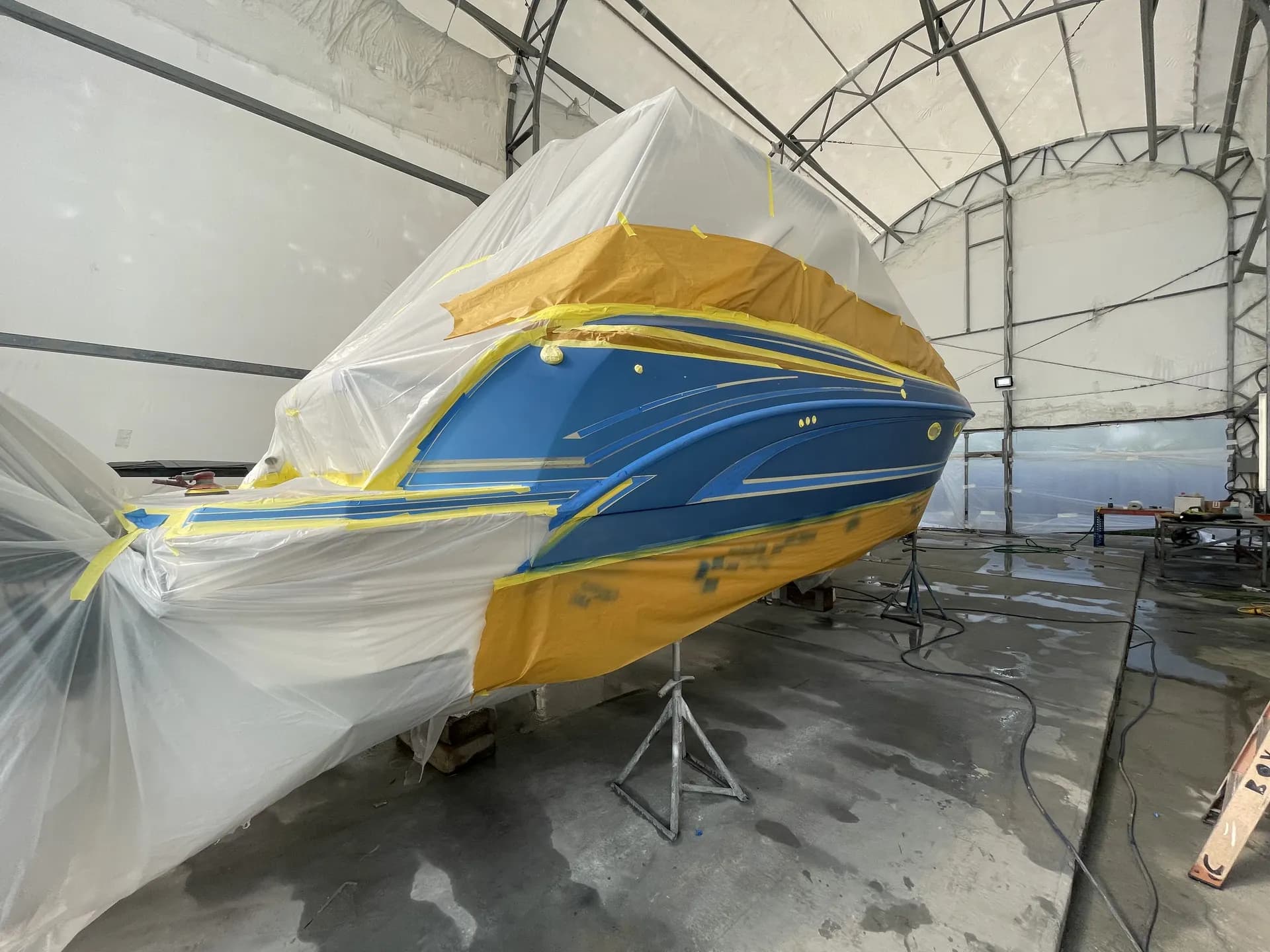 Mid-hull section of a blue powerboat fully masked for refinishing work