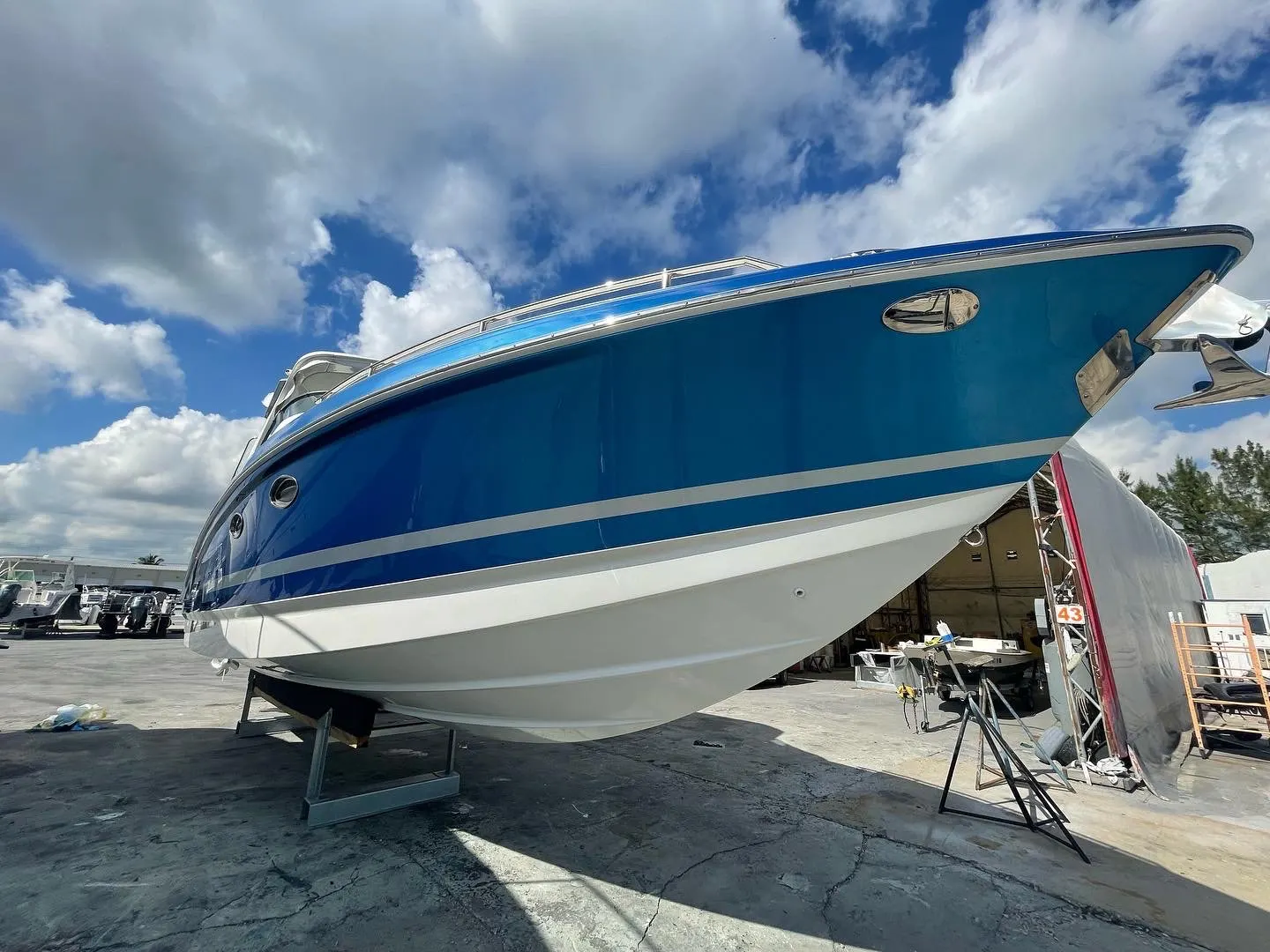 Bow of a powerboat with a mirror-gloss blue and white hull finish in a dry-dock setting