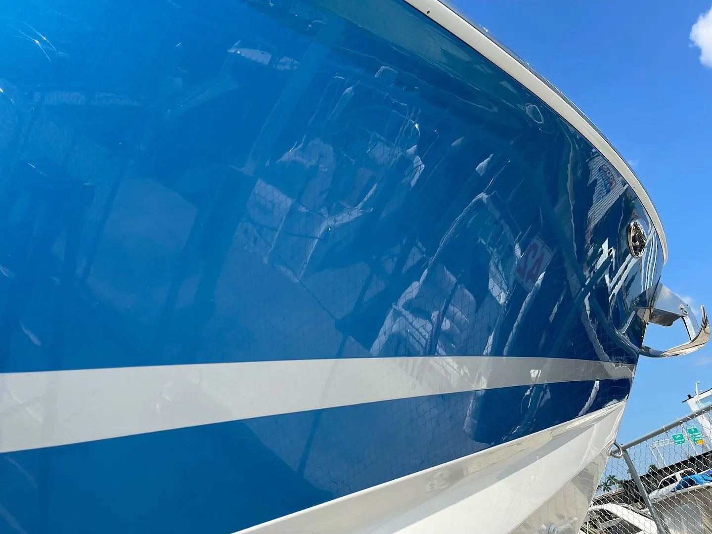 Close view of a high-gloss bow finish reflecting sky and yard light after refinishing