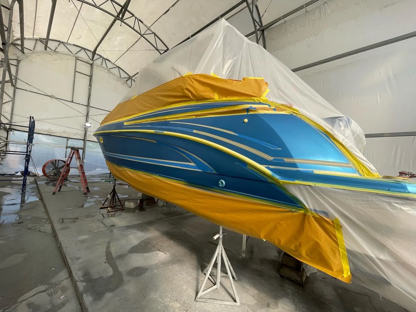 Hull graphics masked with protective tape during marine refinishing preparation