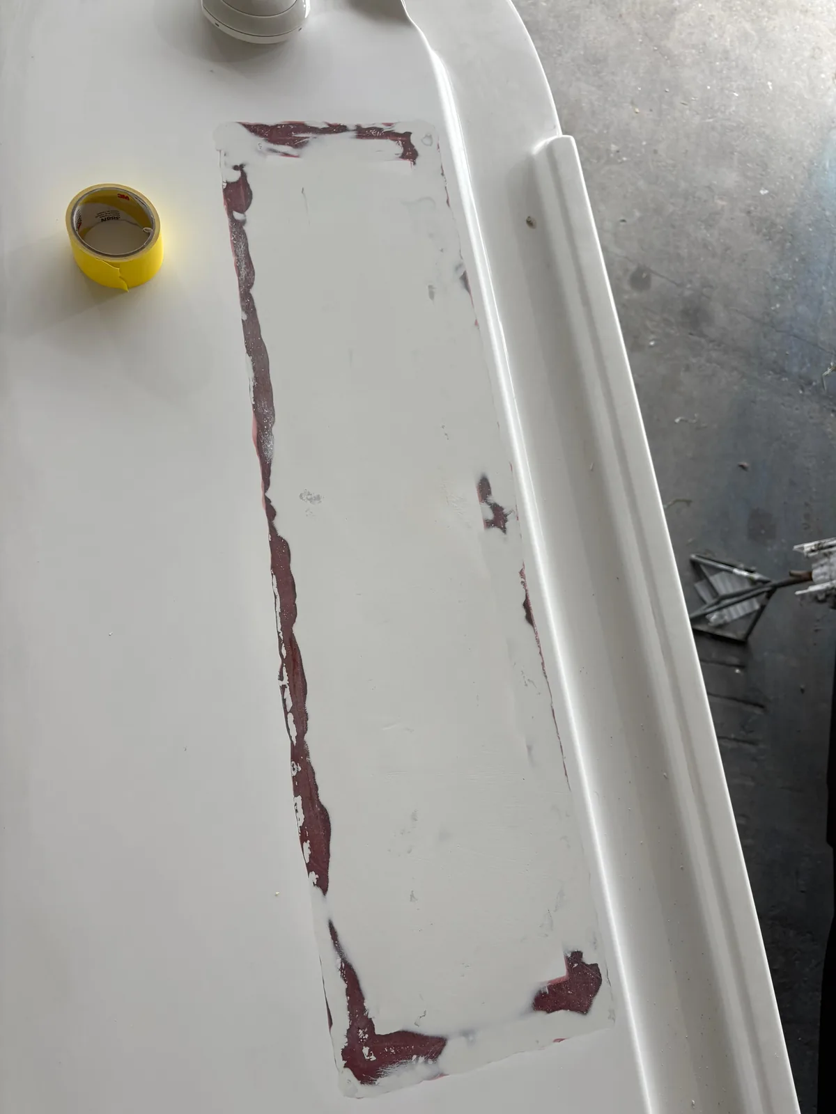 Sanded fairing patch on a white fiberglass hardtop surface during bodywork